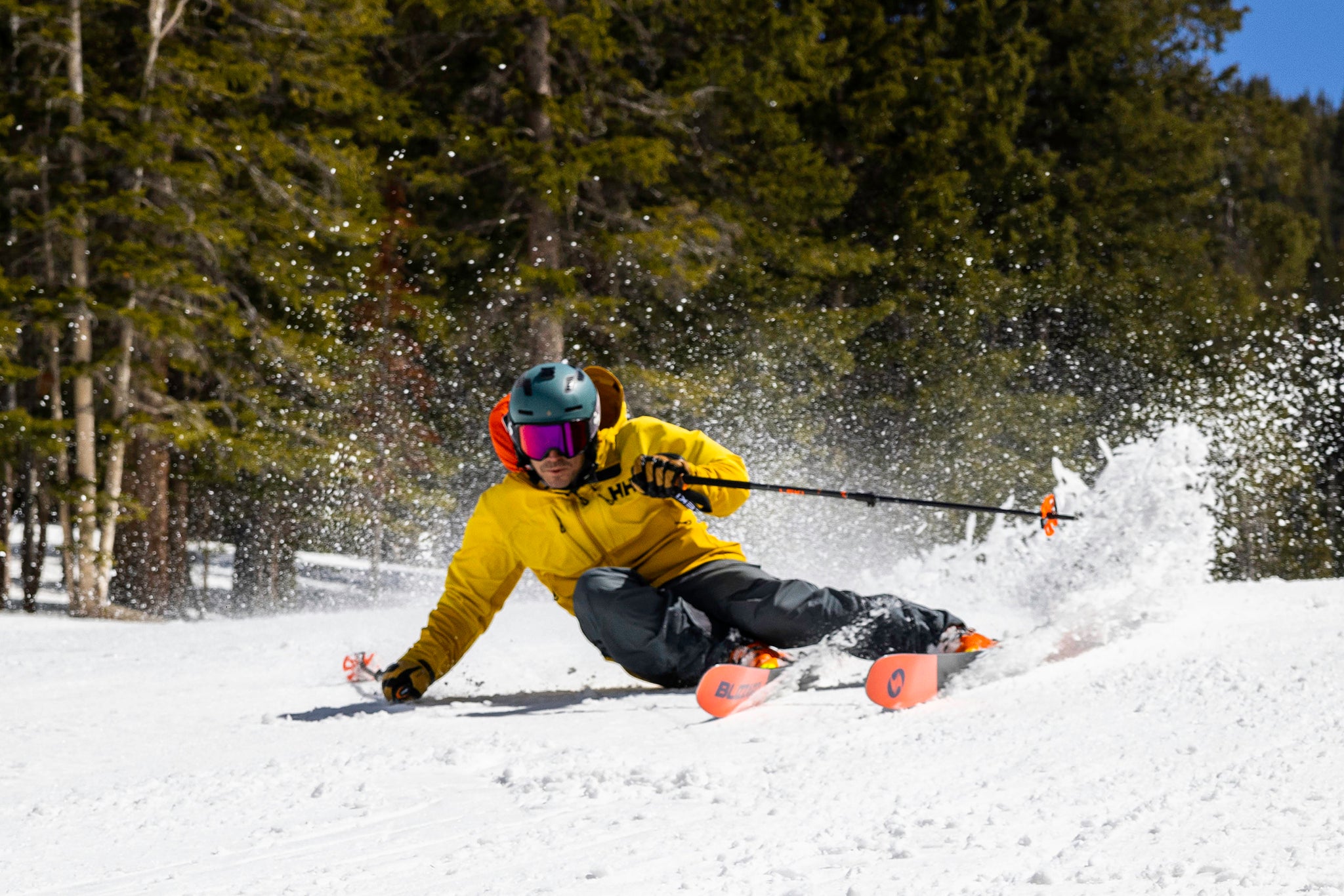 Action photo of a skiier making a sharp turn on a slope, wearing a helmet with the Cardo Packtalk OUTDOOR Communication System fitted to talk with friends or skiing students