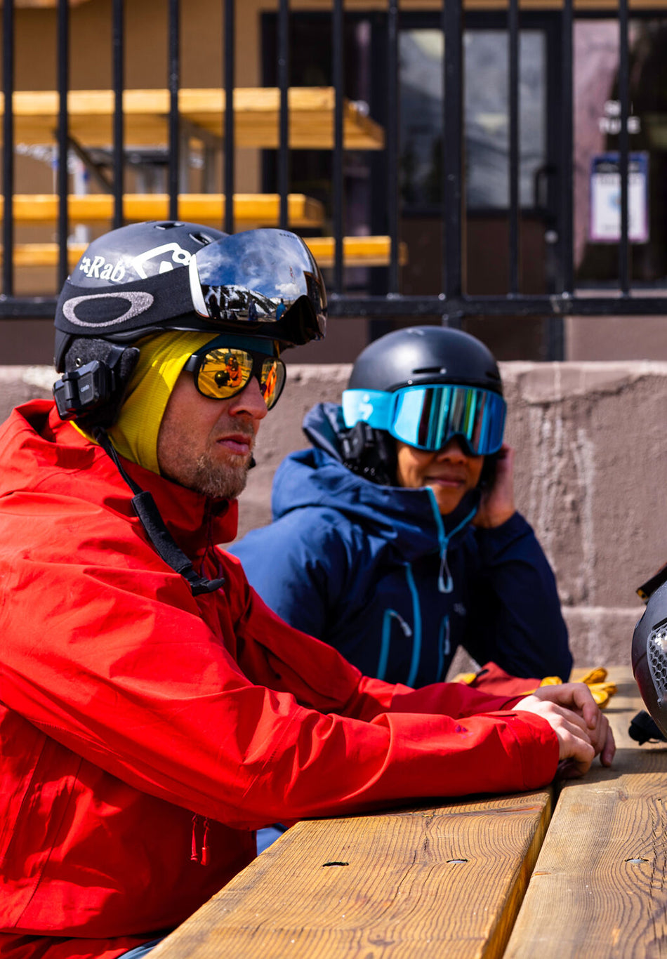 Lifestyle photo of skiers sitting at a table and talking, with Cardo Communication Systems attached to their helmets