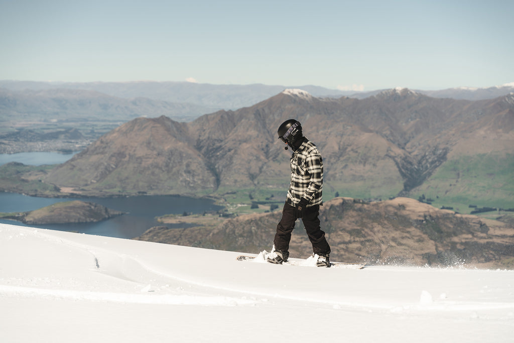 Action photo of a snowboarder on a snowy mountain, wearing a helmet with a Cardo Packtalk OUTDOOR Communication System